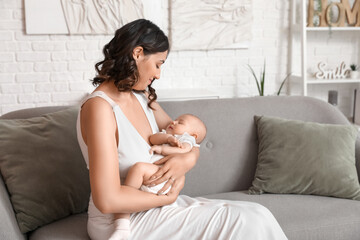 Sticker - Young woman with her baby sitting on sofa at home