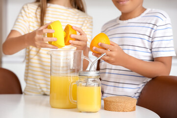 Sticker - Little children making fresh orange juice at table in kitchen