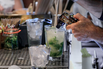 Bartender making a mojito cocktail with fresh lime and mint at a restaurant bar in Huntington Beach, Orange County, California, USA