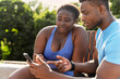 © Maria Vitkovska - Positive young couple, African man and woman holding mobile phone
