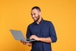 © New Africa - Smiling young man working with laptop on yellow background