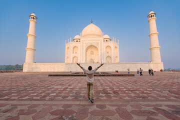 The man with arms around his back standing in front of Taj Mahal indian palace. Islam architecture. 