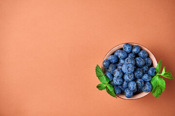 Wall Mural - Blueberries in a ceramic bowl on an orange background. View from above
