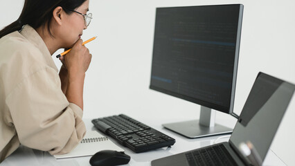 Wall Mural - developer programmer holds pencil and checking code on monitor while programming to developing web