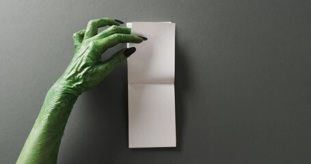 Poster - Video of halloween green monster hands and notebook with copy space on grey background