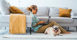 Domestic lifestyle people and animal together in friendship and life. One woman working on laptop sitting on the carpet at home with best friend dog relaxing near. Living room interior. Leisure.