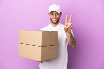 Wall Mural - Delivery caucasian man isolated on purple background smiling and showing victory sign