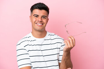 Wall Mural - Young caucasian handsome man isolated on pink background With glasses with happy expression