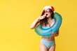 © Богдан Маліцький - shocked girl in swimsuit and sunglasses in santa hat and with inflatable swimming circle is surprised
