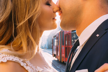 Closeup kissing of newlyweds and tram between them. city street.