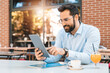 © Dorde - Businessman sitting outdoors  and having a coffee during the sunny day. He is reading a good news for his new big project.