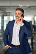 © Stock 4 You - Middle aged Latin or Indian businessman having call on smartphone with business partners or clients. Smiling mature Hispanic man in relaxing pose talking by mobile cellphone at work in office vertical
