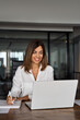 © Stock 4 You - Middle-age Hispanic woman using laptop computer for business studying, watch online virtual webinar training meeting,video call. Focused mature 40s years Latin businesswoman work in office, vertical
