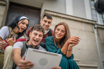 group of students sit in front of school watch video on digital tablet
