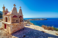 Typical Greek Miniature Roadside Shrine. Small Greek Orthodox Chapel At Crete With Sea Background.