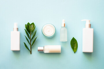 Wall Mural - Natural cosmetic products. Cream, serum, tonic with green leaves. Top view on blue background.