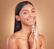 © Ilzer/peopleimages.com - Portrait, woman and touch face for skincare, aesthetic glow and smile for clean dermatology on brown background. Happy indian model, natural beauty and shine in studio for self care of facial results