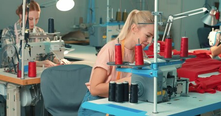 Wall Mural - young caucasian blonde and ginger females tailors using sewing machine. happy women working as seamstress in clothing factory, clothing production concept. dressmaking, tailoring in workshop, job