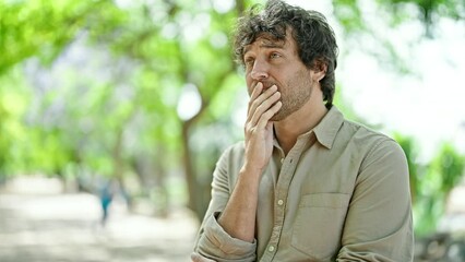 Wall Mural - Young hispanic man standing with doubt expression at park