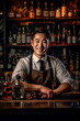 © Canvas Alchemy - Young smiling Korean bartender on the workplace. Shelves with bottles of alcohol in the background