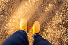 Yellow Boots Work By Woman In Jeans Looking Down On Dusty Dry Land With Soft Fluffy Dirt