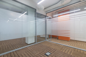 Modern design of an office space with glass partitions. Brown floor covering with an .original pattern.