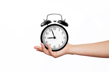 Female hand holding a black alarm clock isolated on white background. 9 o'clock. Morning, reminder. Time concept