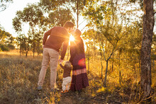 Husband And Wife Kiss In Paddock With Golden Sun Flare And Toddler