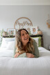 © Austockphoto - Smiling  woman lying on  the bed, looking away from camera