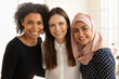 © fizkes - Portrait of smiling multiethnic female employees colleagues hug embrace pose together in international office, happy diverse multiracial women interns students show unity and friendship in relations