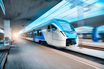 Wall Mural - Blue high speed train in motion on the railway station. Fast moving modern intercity train and blurred background. Railway platform. Railroad in Slovenia. Commercial. Passenger railway transportation