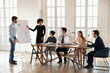 © fizkes - Confident male and woman coach speaker talk make flip chart presentation for multiracial businesspeople at office briefing, trainers present business project on whiteboard for employees at meeting