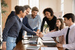 © fizkes - Overjoyed young multiracial colleagues give fist bump motivated for shared team business win or success in office, happy diverse coworkers participate in teambuilding activity at meeting together