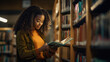 © Studio Nova - Female student standing in front of book shelves in college library and reading book