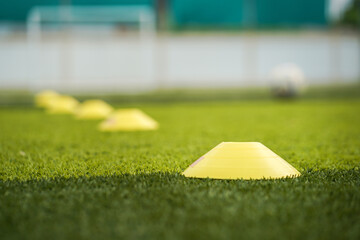 Wall Mural - Obstacle cone for speed and moving training on artificial turf ground for football training. Sport equipment object photo. Selectived focus at the front cone.