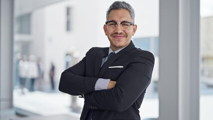 Canvas Print - Young hispanic man business worker smiling confident standing with arms crossed gesture at office