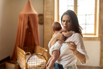 worried mother checking temperature of her little newborn baby, looking at electronic thermometer, b
