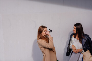 Wall Mural - A blonde girl is putting her friend's sunnglasses on, to see how they look on her