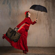 A stylish lady in a red old-fashioned suit with a hat and a lace umbrella