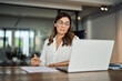 Mid aged business woman having hybrid meeting working in office. Busy mature female corporate leader executive, hr manager communicating by conference call, remote online job interview on laptop.