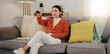 © Wesley/peopleimages.com - Watching tv, relax and an Asian woman on a sofa in the living room of her home streaming a subscription service. Television, channel surfing and comedy with an attractive young female sitting in her