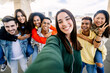 © Xavier Lorenzo - Young group of diverse students having fun together outdoors. Beautiful woman smile at camera taking selfie portrait with diverse friends on the background. Youth community concept.