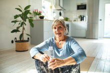 Senior Caucasian Woman Drinking Water After Doing Yoga And Working Out At Home