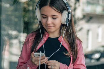 Wall Mural - teen girl with headphones and mobile phone outside