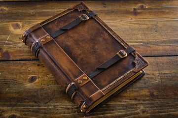 Wall Mural - Aged Leather Book Cover with Closure Belts - Captured on a Wooden Table