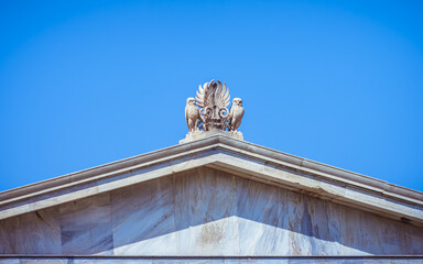 Statuettes of two Athenian Owls on the pediment of the University of Athens, Greece. The little owl is closely associated with the Greek goddess Athena, and hence represents wisdom and knowledge.