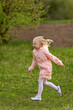© somemeans - Portrait of little European girl with blonde hair in pink outfit running across field. Vertical frame.