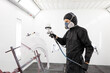© AvokadoStudio - Worker in protective uniform spraying car body part in white paint