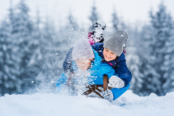 Wall Mural - Happy sports family, children have fun sledding in winter. Winter active outdoor games. Wonderful winter landscape background.