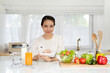Nutritionist sitting at desk with fruit and vegetable, working on diet plan. Healthy eating, right nutrition and diet concept . Smiling asian woman in kitchen with healthy food looking at camera.
